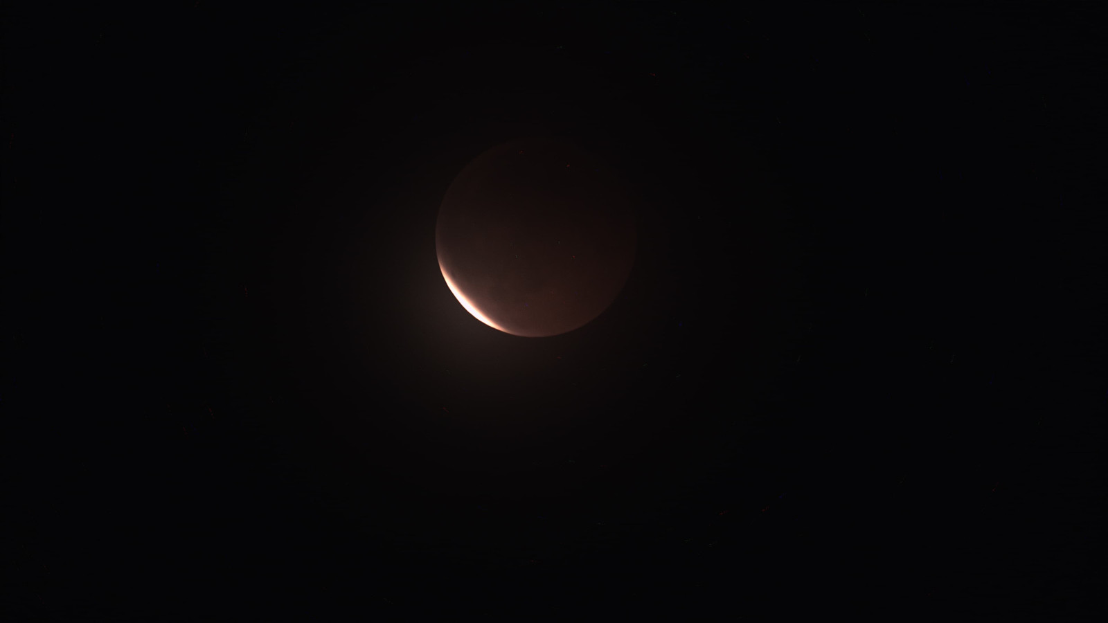 Ein teilweise von Schatten bedeckter Mond, umgeben von dunklem Nachthimmel.