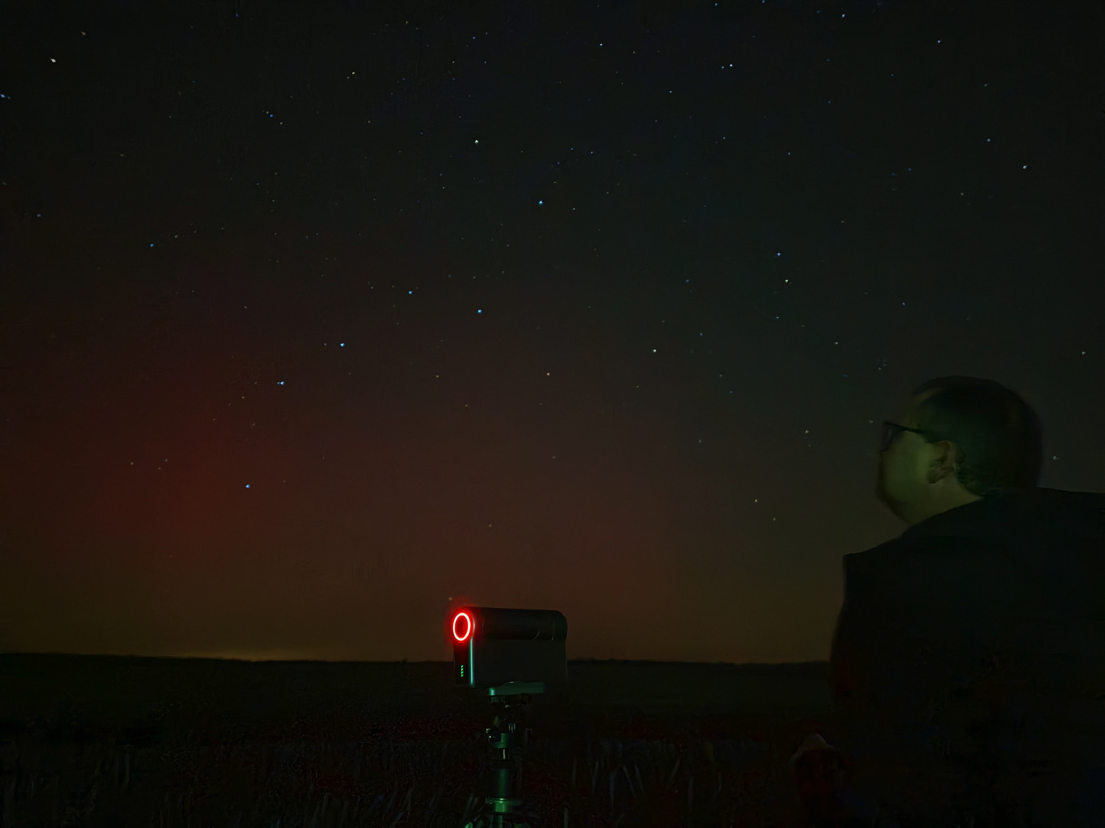 Person, die nachts mit einem Teleskop den Sternenhimmel beobachtet.